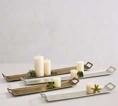 three metal trays with candles and succulents on them