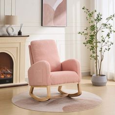 a pink rocking chair sitting in front of a fire place next to a plant on a rug