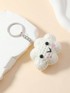 a crocheted keychain with a small white animal on it's face