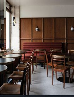 an empty restaurant with wooden tables and chairs in front of wood paneled wall panels