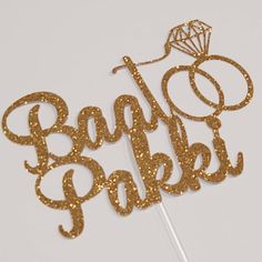 a cake topper with the words baby bakes spelled in gold glitter on it