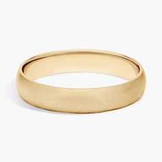 a yellow gold wedding ring with a thin band on a white background, it has a slight edge