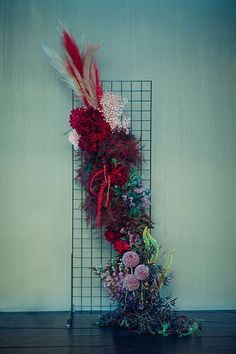 a bunch of flowers that are sitting on a shelf next to a wire rack with feathers