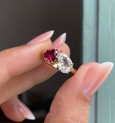 a woman's hand holding an engagement ring with two pear shaped diamonds