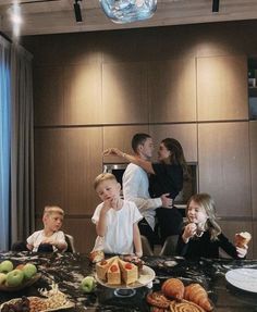 a group of people sitting around a table with cakes and pastries in front of them