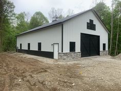 a large white barn with black doors and windows