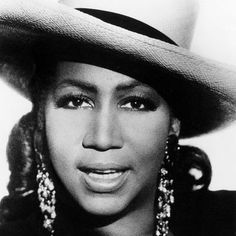 a black and white photo of a woman wearing a hat with large earrings on it