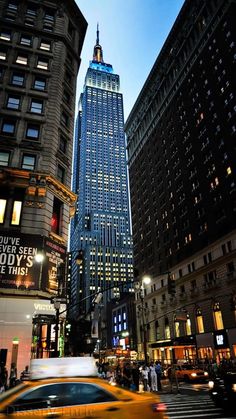 a taxi cab driving down a street next to tall buildings in new york city at night