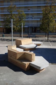 three concrete benches sitting in front of a tall building on the side of a road