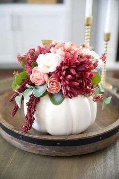 a white pumpkin filled with flowers on top of a wooden table