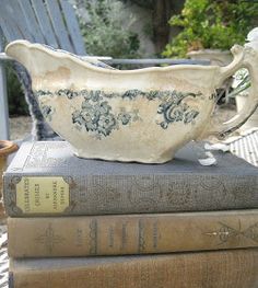 three books stacked on top of each other with a white bowl sitting on top of them