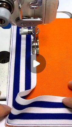 someone is using a sewing machine to sew on an orange and blue striped fabric