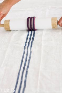 a person is rolling up some fabric on the floor with two rolls of tape next to them