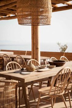 an outdoor dining area with wicker chairs and table set for four, overlooking the ocean