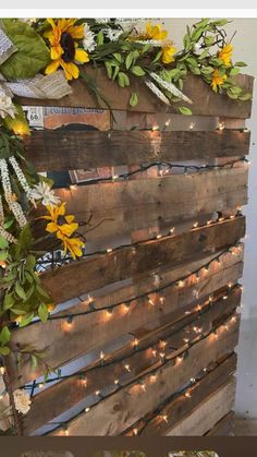 an old pallet is decorated with sunflowers and greenery