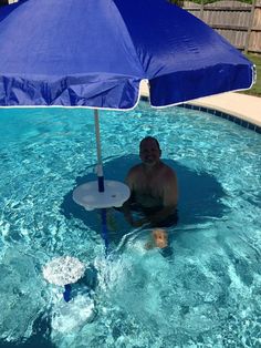 a man is sitting under an umbrella in the pool