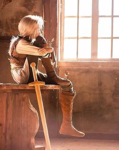 a woman sitting on top of a wooden bench next to a window with sunlight streaming through it