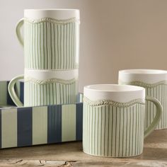 three green and white striped mugs sitting next to each other on a wooden table