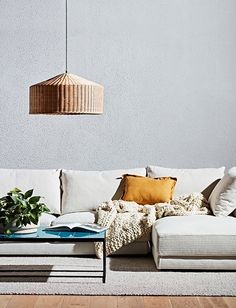 a white couch sitting on top of a wooden floor next to a table and lamp