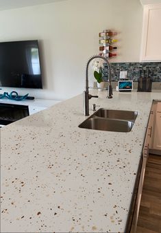 a kitchen counter top with a tv in the background