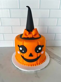 an orange cake with a black hat on top