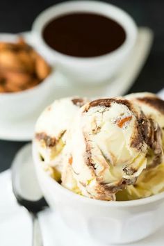 a bowl filled with ice cream next to two cups of coffee