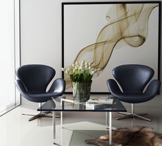 three chairs and a coffee table in a room with a large painting on the wall