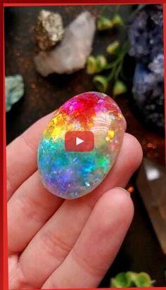 a hand holding a rainbow colored object in it's left hand with the video below