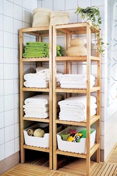 a bamboo shelf filled with lots of white towels and other household items in a bathroom