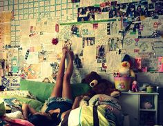 two people laying on a bed in front of a wall covered with posters