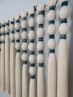 a row of wooden dowels hanging on a wall next to strings of wood beads