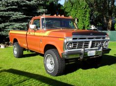 an orange truck parked on top of a lush green field