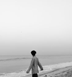 a man standing on top of a beach next to the ocean