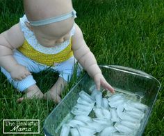 a baby is sitting in the grass and reaching for something with it's hands