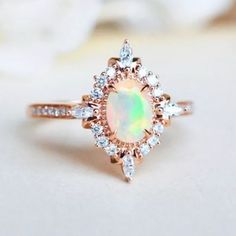 an opal and diamond ring on a white surface