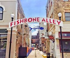 a fishbone alley sign hanging from the side of a building in an alleyway