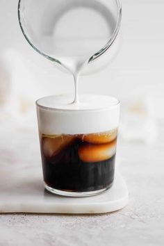 coffee being poured into a glass with liquid