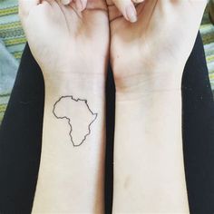 two hands with wrist tattoos that have the shape of africa on them