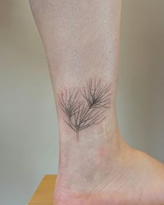 a small pine tree branch tattoo on the ankle