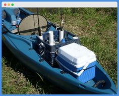 a blue kayak sitting in the grass with an air compressor on it's side