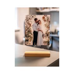 a wooden block sitting on top of a table next to a photo and a pen