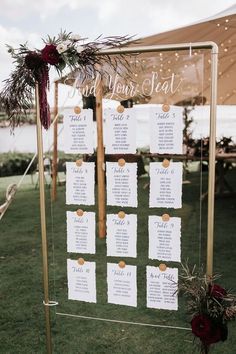 the seating chart was set up on a gold frame with greenery and red flowers