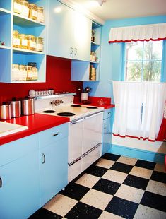 a kitchen with red and blue walls, white cabinets and black and white checkered flooring