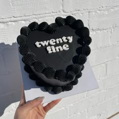 a heart shaped cake with the words twenty nine on it, held by a woman's hand