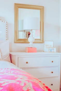 a bedroom with a dresser, mirror and lamp on the side table in front of it