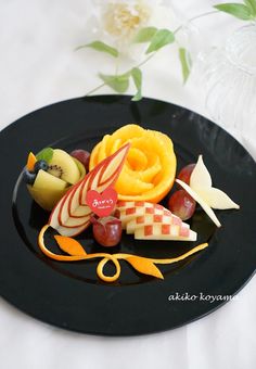 a black plate topped with fruit and veggies