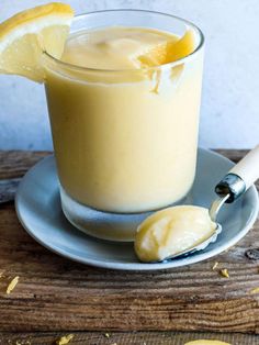 a glass filled with lemonade sitting on top of a plate next to sliced lemons