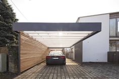 a car is parked under an awning in a driveway with brick pavers on the ground