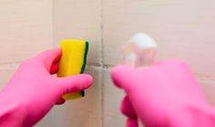 a person in pink gloves cleaning a wall with a sponge