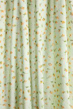 a close up view of a curtain with flowers on the top and bottom, in light green